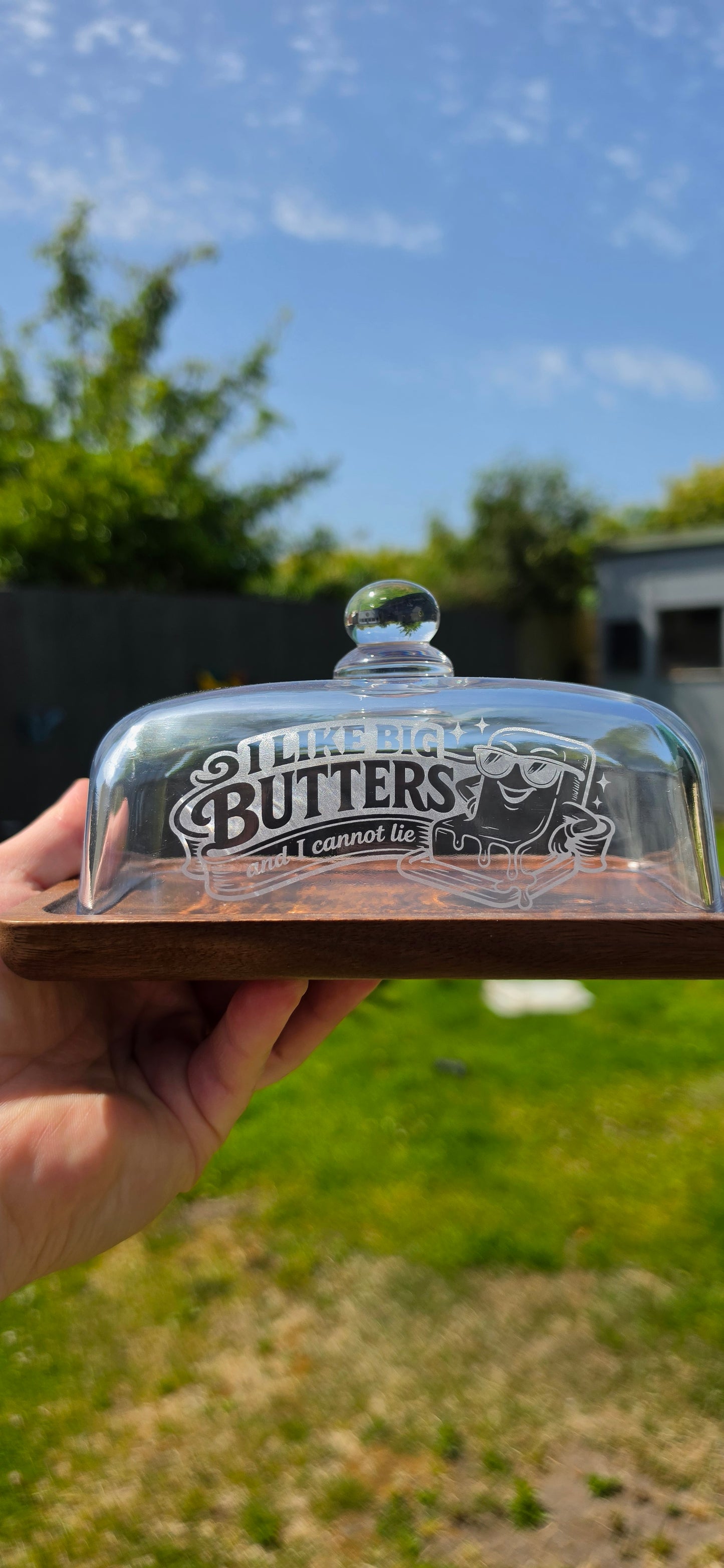 Butter dish with lid held by a hand against a blurred outdoor background