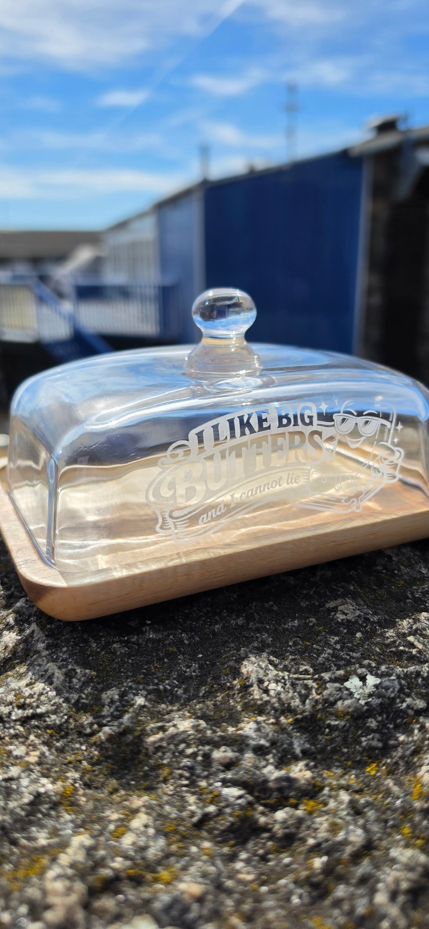 Clear glass butter dish with a label on a stone surface