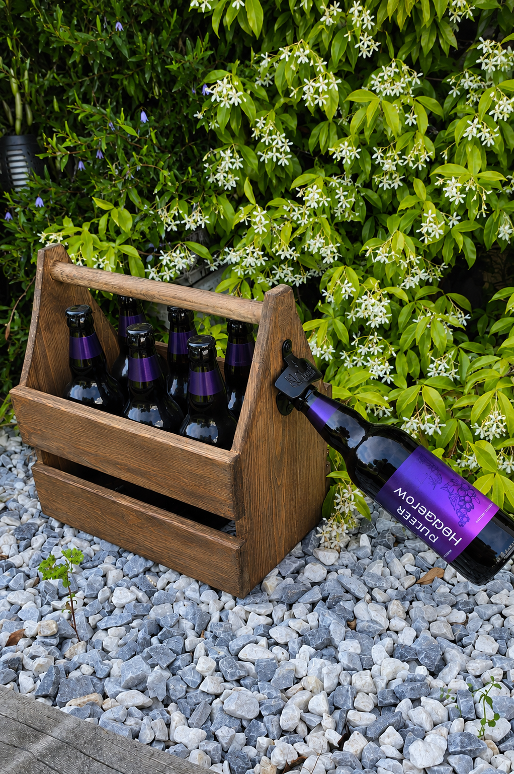 Wooden crate with beer bottles on a gravel surface with greenery in the background